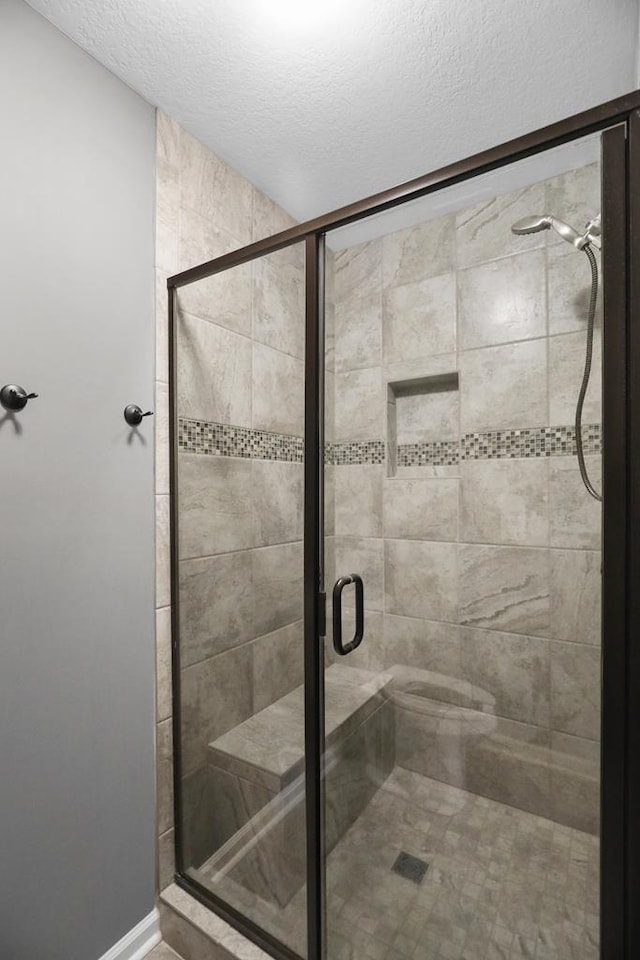 bathroom with a shower stall and a textured ceiling