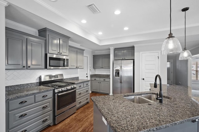 kitchen with visible vents, an island with sink, stainless steel appliances, gray cabinetry, and a sink