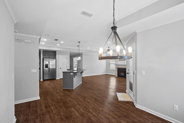 kitchen featuring a breakfast bar, open floor plan, dark countertops, stainless steel fridge, and pendant lighting