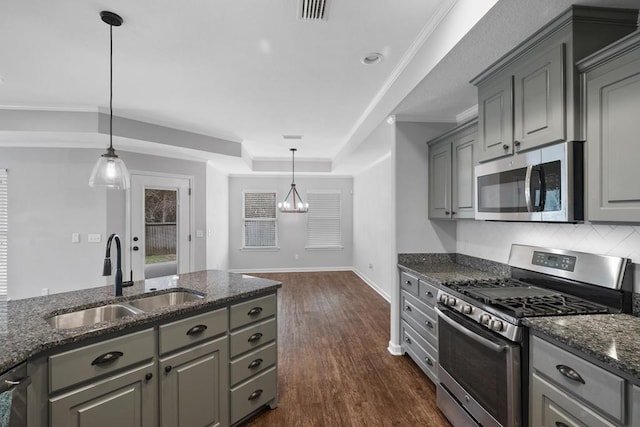 kitchen featuring appliances with stainless steel finishes, gray cabinets, a sink, and hanging light fixtures