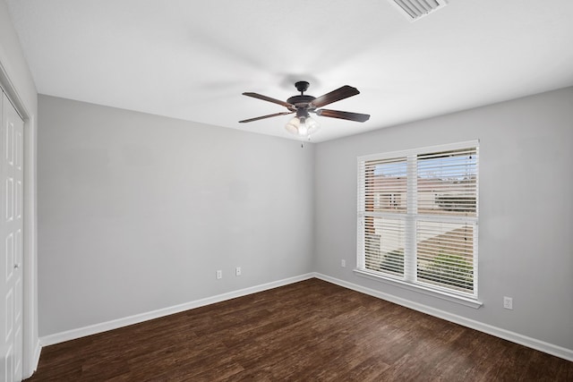 spare room featuring dark wood-style floors, baseboards, visible vents, and ceiling fan