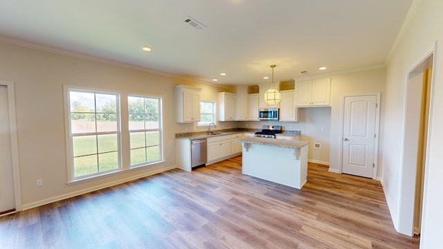 kitchen with light wood-type flooring, stainless steel appliances, sink, white cabinets, and a kitchen island