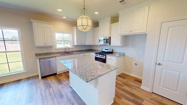 kitchen with sink, white cabinets, pendant lighting, a kitchen island, and appliances with stainless steel finishes