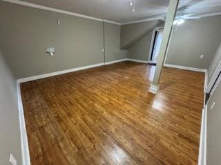 below grade area featuring baseboards, wood finished floors, and a ceiling fan
