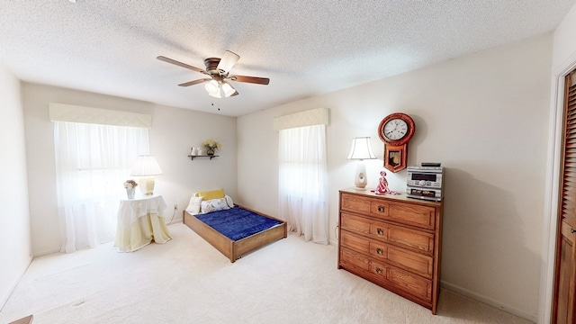 bedroom with light colored carpet, a textured ceiling, and a ceiling fan