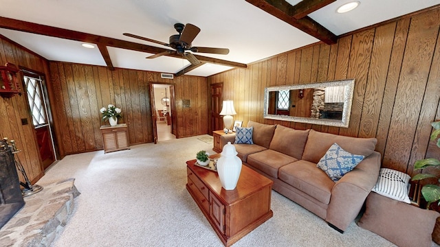living area featuring beam ceiling, wooden walls, a ceiling fan, and light carpet