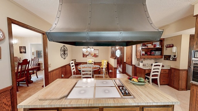 dining area featuring a wainscoted wall, a textured ceiling, wood walls, and a chandelier