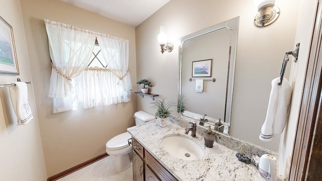 bathroom featuring toilet, vanity, tile patterned flooring, and baseboards