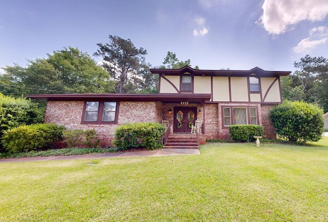 tudor-style house with brick siding and a front yard