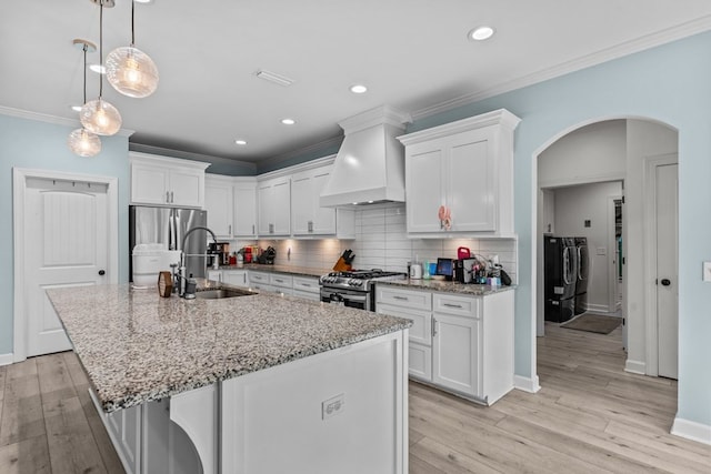 213 Archer Trl, Enterprise, AL 36351 - kitchen with washer and clothes dryer, arched walkways, custom range hood, a sink, and appliances with stainless steel finishes