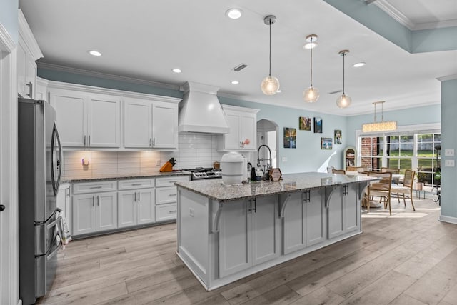 213 Archer Trl, Enterprise, AL 36351 - kitchen with decorative backsplash, crown molding, arched walkways, premium range hood, and freestanding refrigerator