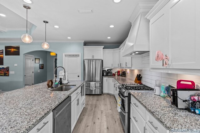 213 Archer Trl, Enterprise, AL 36351 - kitchen featuring custom exhaust hood, arched walkways, white cabinets, a sink, and stainless steel appliances