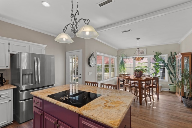 kitchen with white cabinetry, decorative light fixtures, a center island, black electric cooktop, and stainless steel fridge