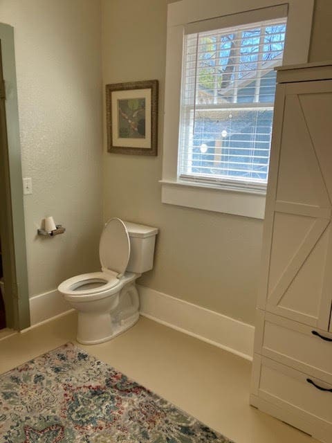 bathroom featuring tile patterned flooring, baseboards, and toilet