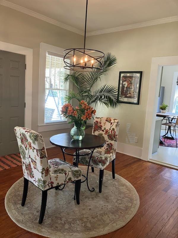 dining room with crown molding, baseboards, a chandelier, and wood finished floors