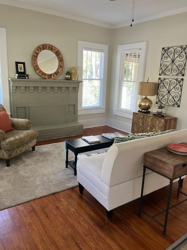 living area featuring baseboards, a fireplace, wood finished floors, and crown molding