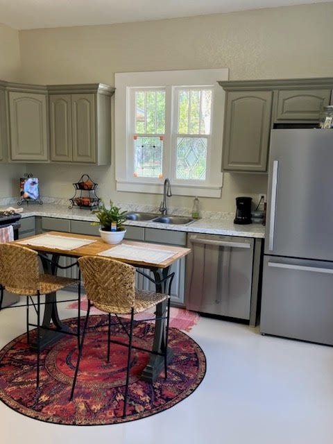 kitchen with stainless steel appliances, light countertops, a sink, and gray cabinetry