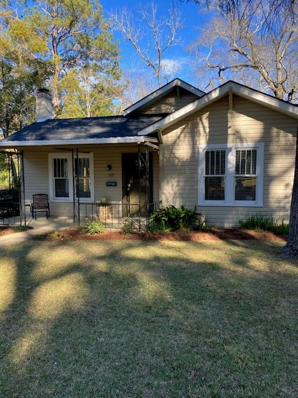 view of front of house with a porch, a chimney, and a front yard