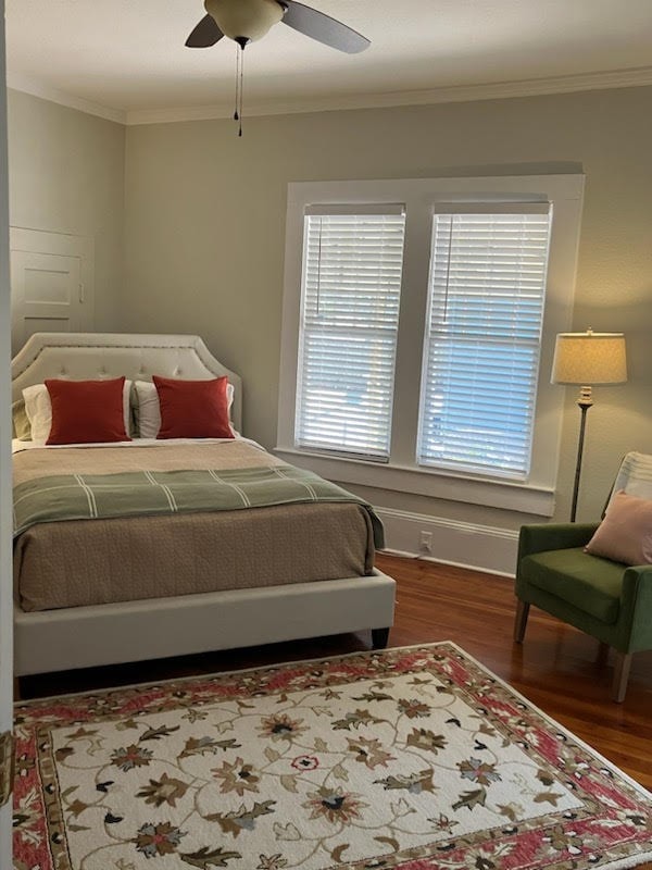 bedroom with ceiling fan, crown molding, baseboards, and wood finished floors