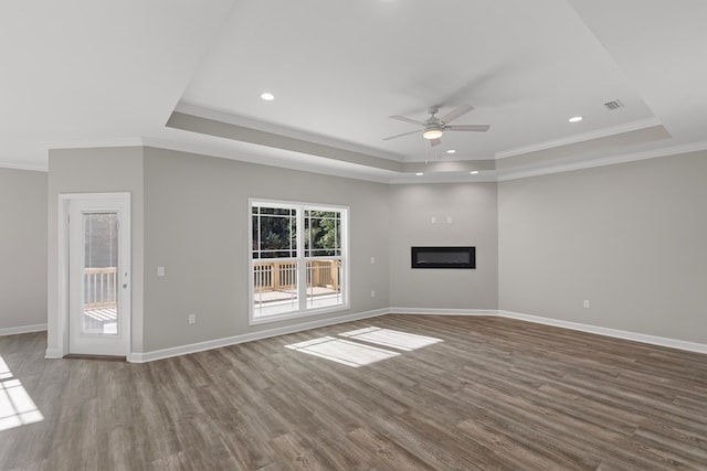 unfurnished living room with a raised ceiling, crown molding, hardwood / wood-style floors, and ceiling fan