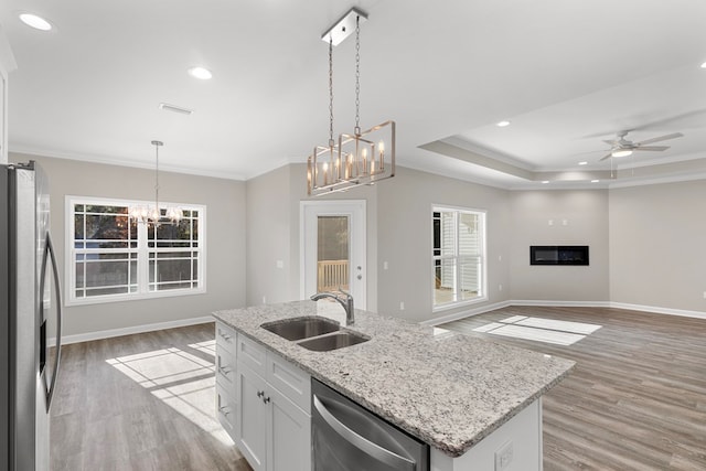 kitchen featuring white cabinetry, sink, hanging light fixtures, light hardwood / wood-style flooring, and appliances with stainless steel finishes