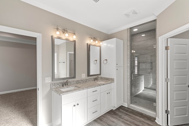 bathroom featuring vanity, wood-type flooring, an enclosed shower, and ornamental molding