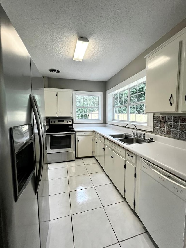 115 Westmont Dr, Dothan, AL 36301 - kitchen with stainless steel appliances, light countertops, a textured ceiling, light tile patterned floors, and white cabinets