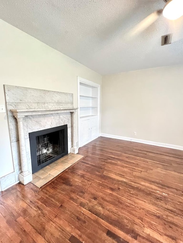 115 Westmont Dr, Dothan, AL 36301 - unfurnished living room featuring a high end fireplace, built in features, wood finished floors, and a textured ceiling