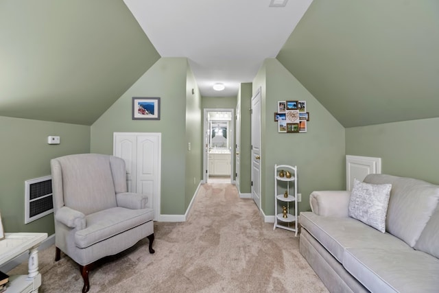 sitting room with lofted ceiling, heating unit, light colored carpet, and baseboards