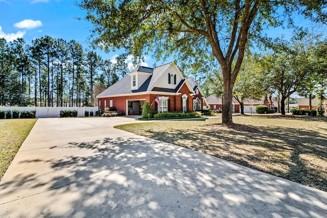 view of front of home featuring a front yard, concrete driveway, brick siding, and fence