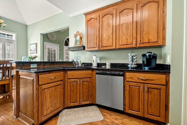 kitchen featuring stainless steel dishwasher, dark stone countertops, a sink, and brown cabinets