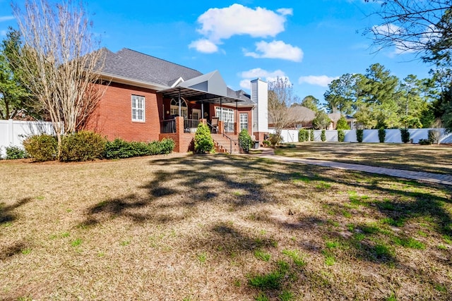 view of front of house with stairway, brick siding, a fenced backyard, and a front lawn