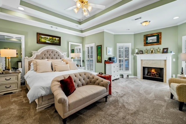 carpeted bedroom featuring recessed lighting, a fireplace, visible vents, a tray ceiling, and crown molding