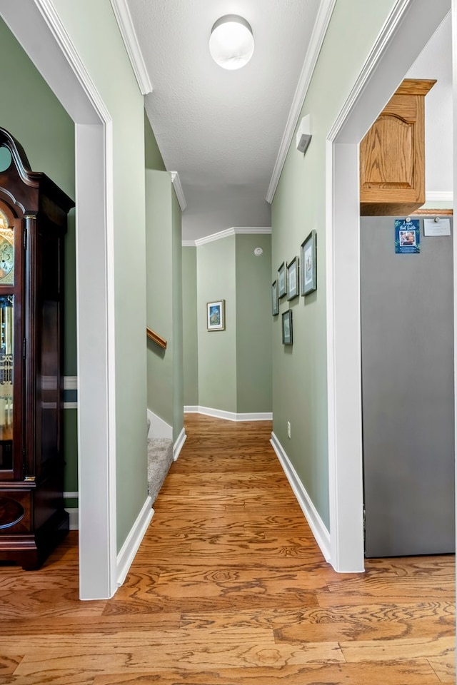 hall with light wood-type flooring, baseboards, stairs, and ornamental molding