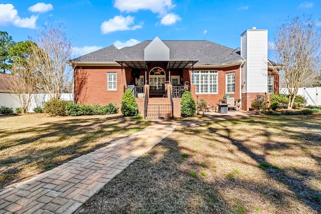 view of front of home with brick siding, a front lawn, and fence private yard