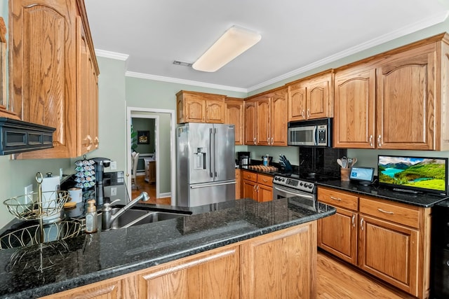 kitchen featuring a peninsula, dark stone counters, stainless steel appliances, and a sink