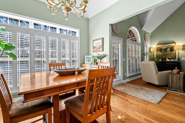 dining space featuring a chandelier, high vaulted ceiling, and wood finished floors