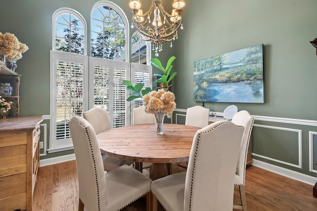 dining space featuring a chandelier, a wainscoted wall, and dark wood finished floors