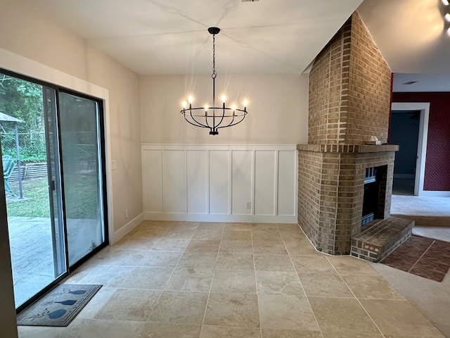 426 Walker Rd, Ozark, AL 36360 - unfurnished dining area with light stone finish floors, a chandelier, a brick fireplace, a decorative wall, and wainscoting