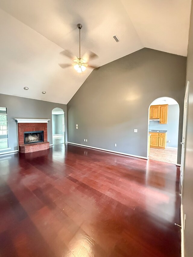 40 Caravan Ln, Kinsey, AL 36303 - unfurnished living room featuring arched walkways, vaulted ceiling, a ceiling fan, wood finished floors, and a brick fireplace