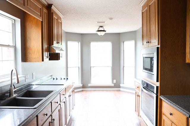 40 Caravan Ln, Kinsey, AL 36303 - kitchen featuring stainless steel appliances, a sink, brown cabinetry, under cabinet range hood, and a textured ceiling