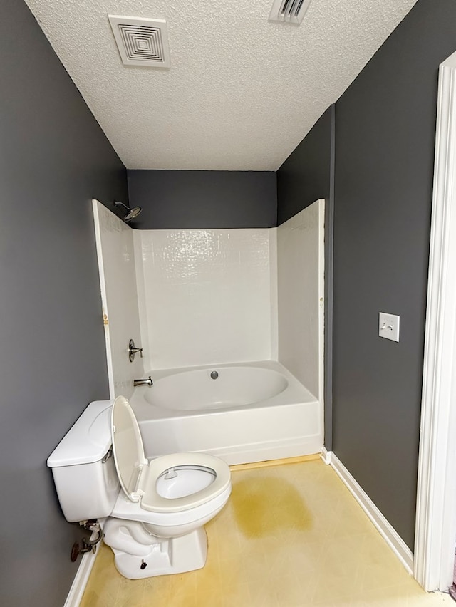 40 Caravan Ln, Kinsey, AL 36303 - bathroom featuring toilet, bathtub / shower combination, baseboards, and a textured ceiling