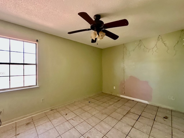 spare room featuring a textured ceiling, ceiling fan, and baseboards