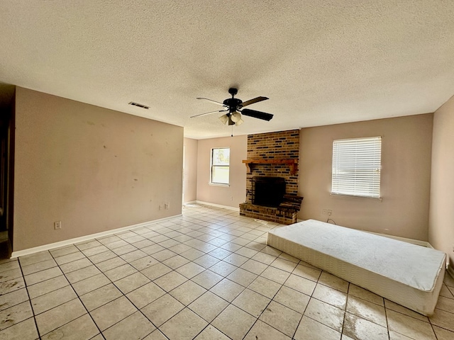 unfurnished living room featuring light tile patterned flooring, a textured ceiling, visible vents, ceiling fan, and a fireplace