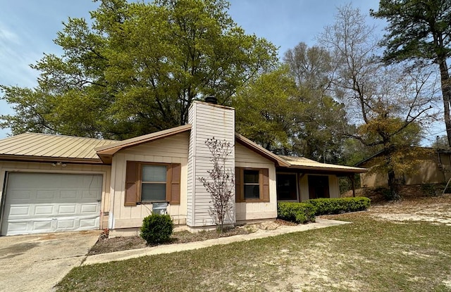view of front of home with a chimney, concrete driveway, a garage, and metal roof