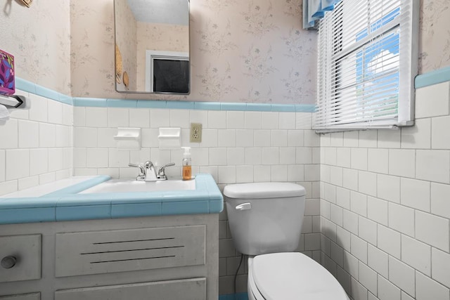 902 Moss St, Dothan, AL 36301 - half bath with wallpapered walls, a wainscoted wall, vanity, tile walls, and toilet