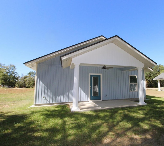 back of property featuring a yard and ceiling fan