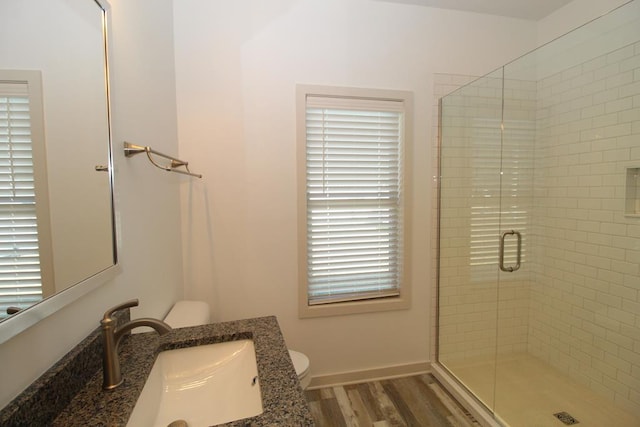 bathroom featuring hardwood / wood-style floors, vanity, toilet, and a shower with door