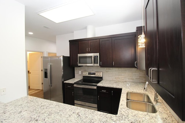 kitchen with sink, stainless steel appliances, light stone counters, backsplash, and light hardwood / wood-style floors