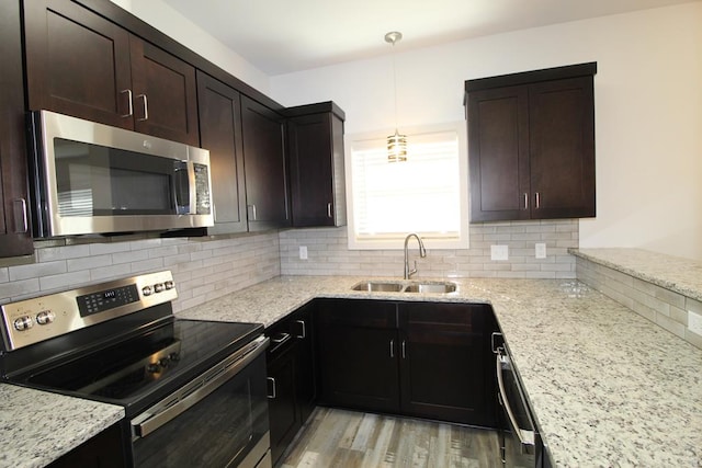 kitchen featuring dark brown cabinets, stainless steel appliances, sink, light hardwood / wood-style flooring, and hanging light fixtures